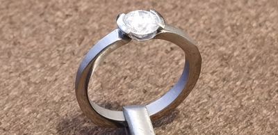 The finished titanium ring standing upright with the diamond tension-set between its two claws
