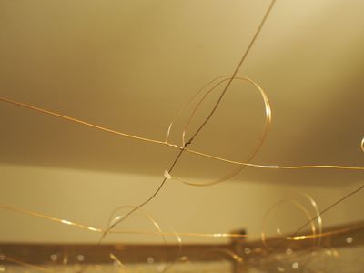 Close-up of thin enamelled copper wires soldered together at a crossing point, part of the charlieplexed LED grid